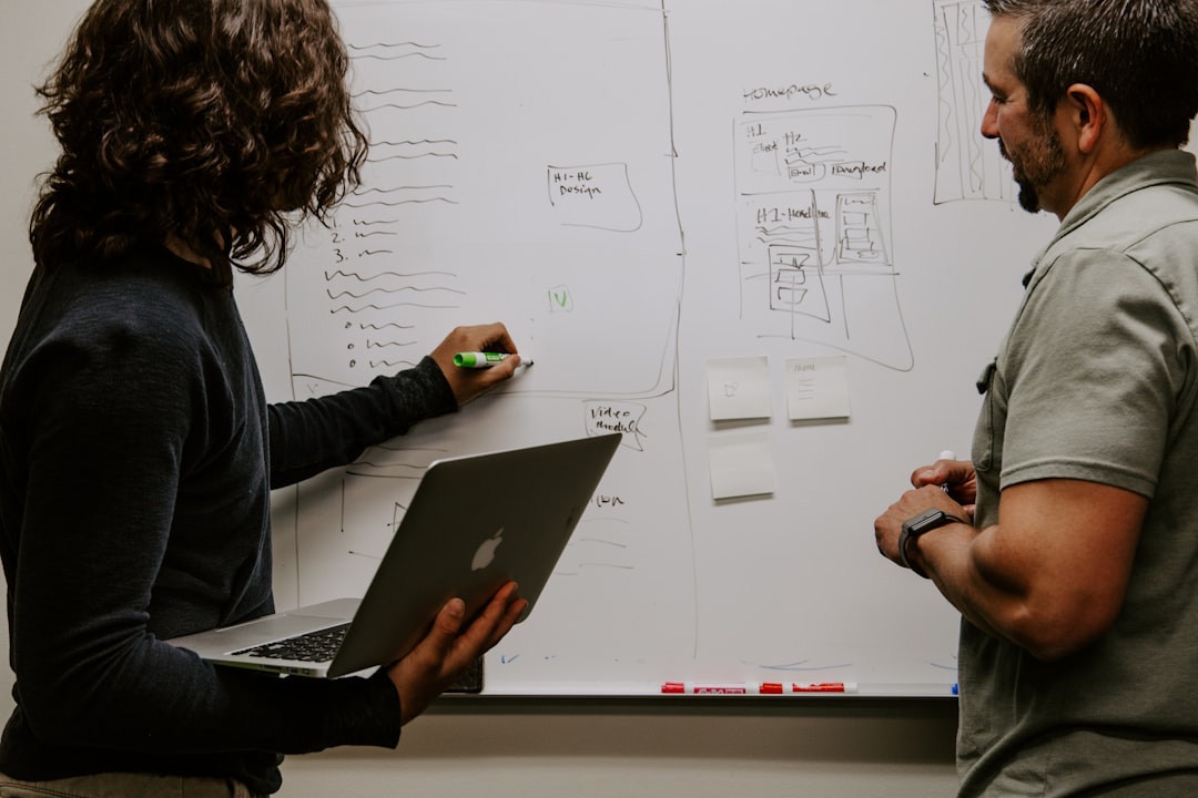 2 Business People discussing Strategy on a Whiteboard.